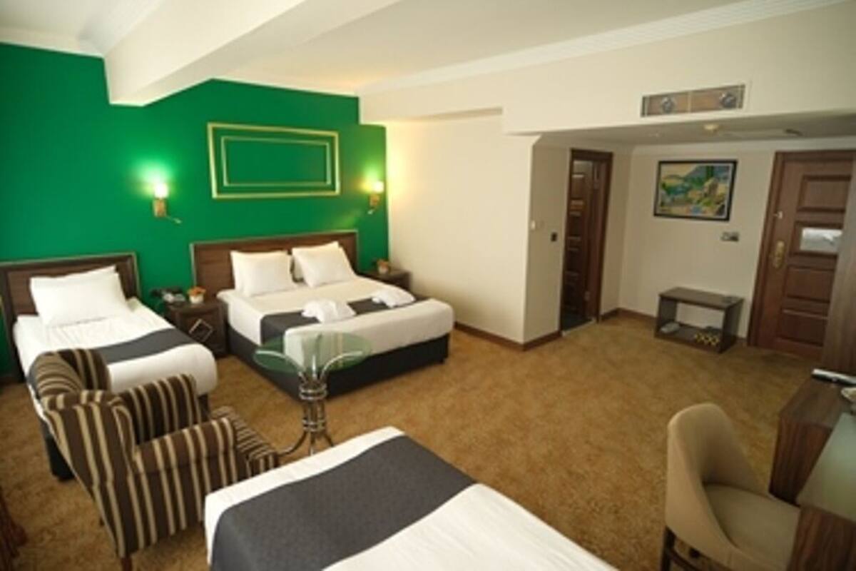 Habitación de hotel con dos camas, un escritorio, una silla y una mesita.