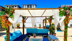 An outdoor seating area with blue cushioned sofas, a small table, and potted plants. - Malabadi Hotel (Diyarbakir)
