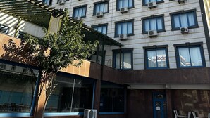 A multi-story hotel building with a modern facade, numerous windows, and a blue entrance door. - Malabadi Hotel (Diyarbakir)