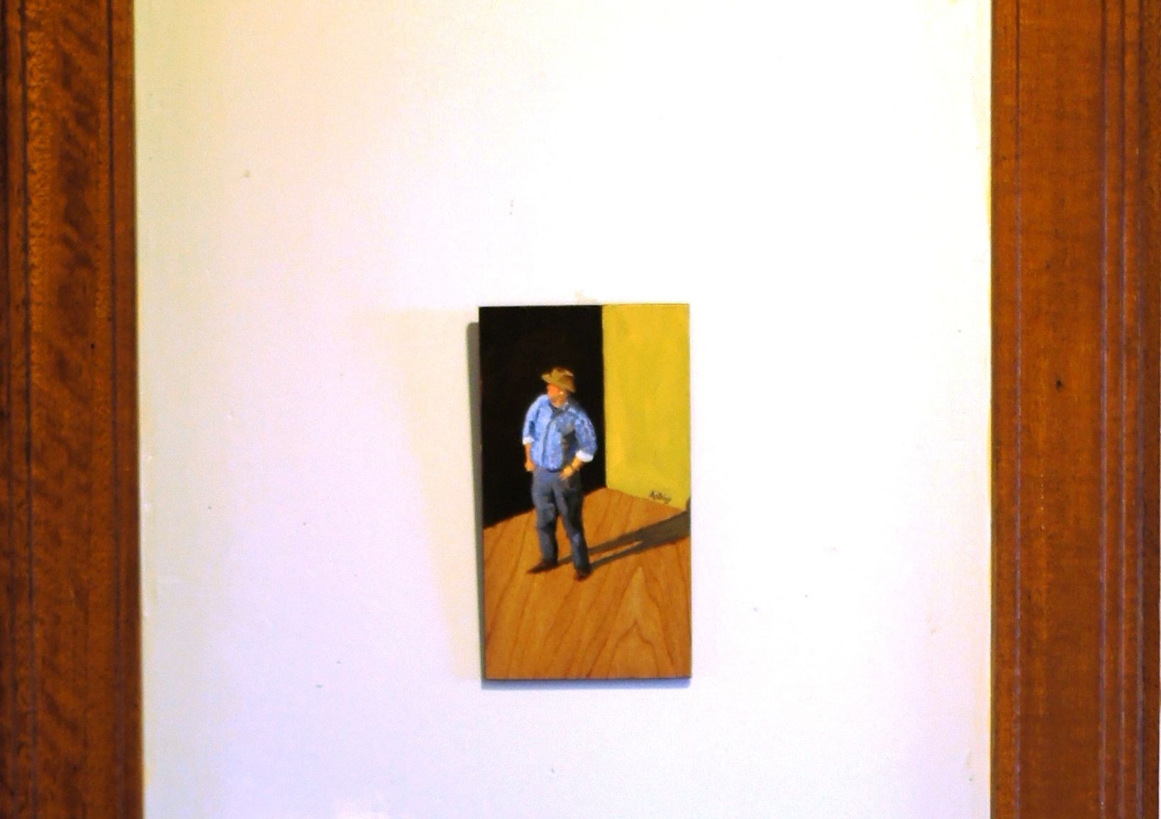 Una pintura muestra a una persona de pie en una habitación con suelo de madera y pared amarilla.