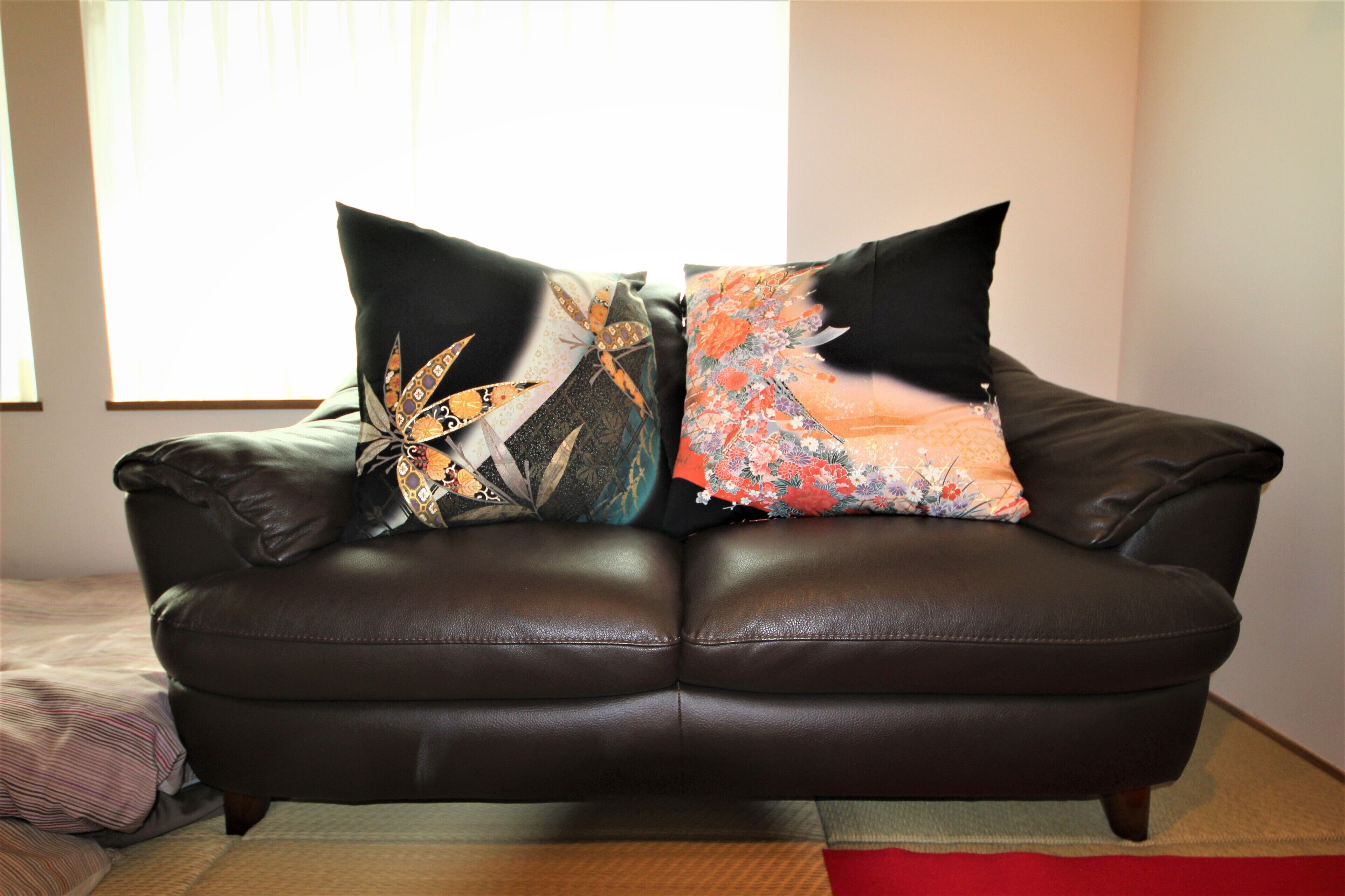 A brown leather sofa with floral and geometric patterned cushions.