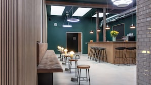 Un área de bar moderna con un banco largo, taburetes e iluminación colgante.