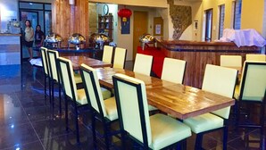 A restaurant with a wooden bar, multiple tables, and chairs.