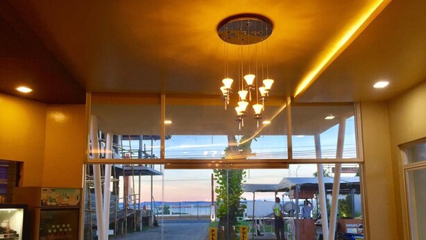 A restaurant with a view of the sea, a chandelier, and a counter with a menu.