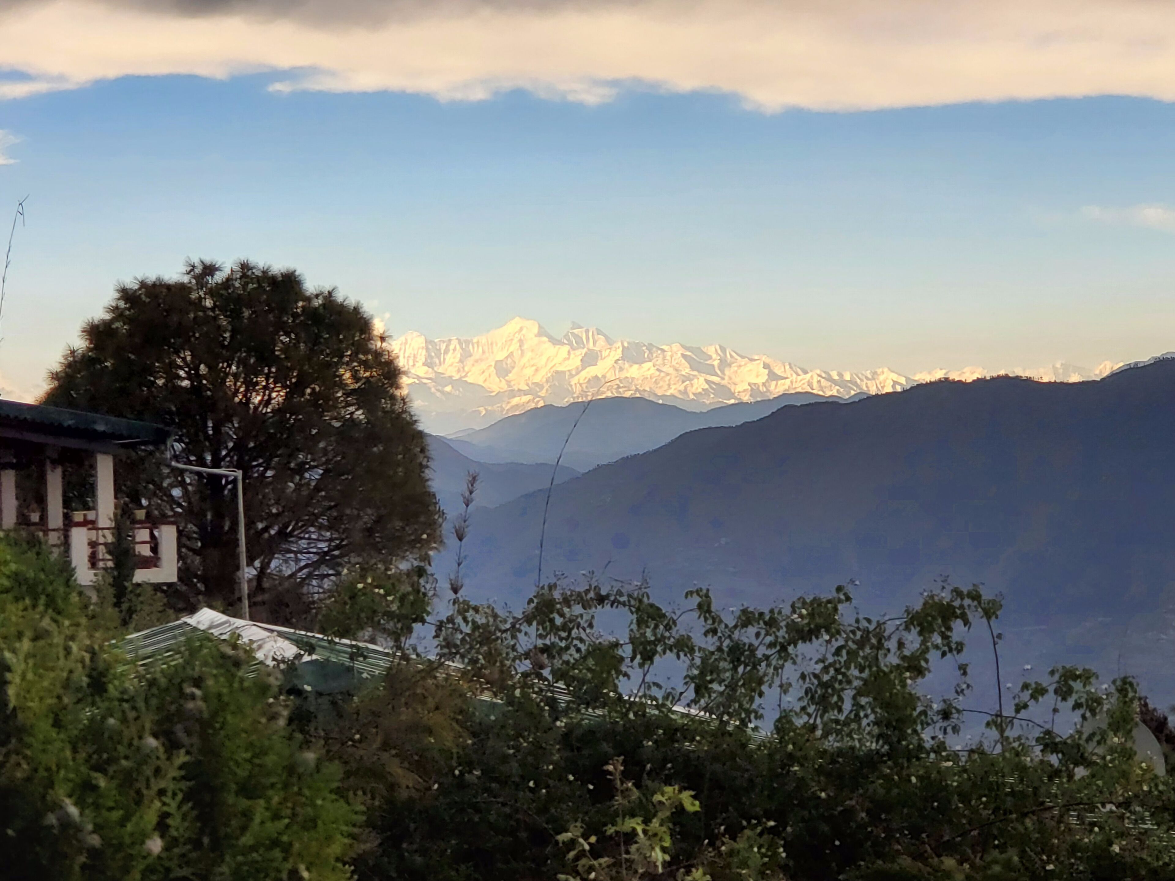 Un paysage de montagne avec des sommets enneigés et un bâtiment au premier plan.