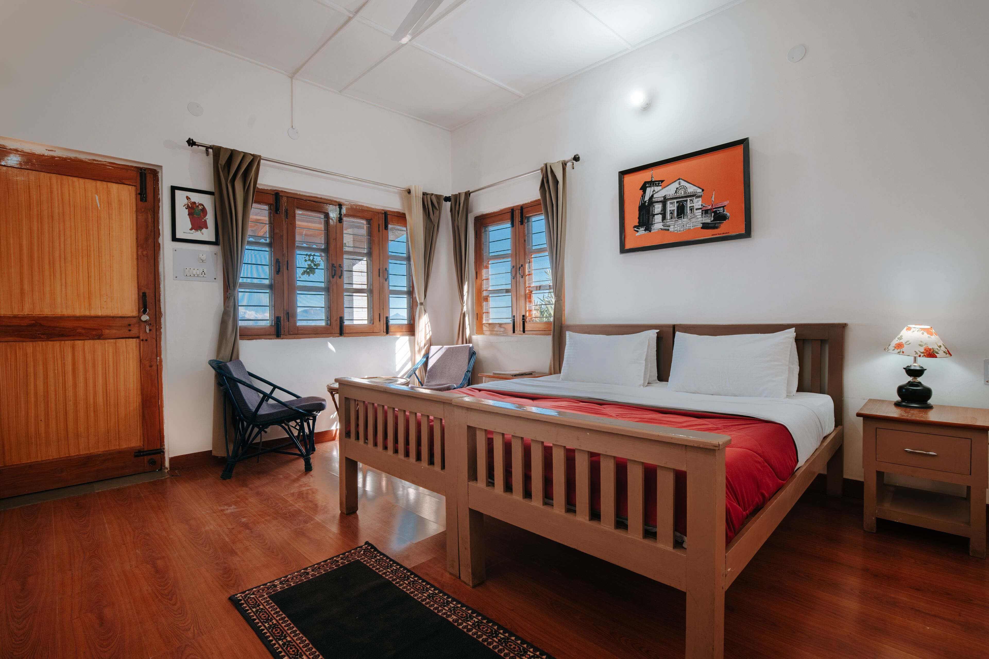 A bedroom with a wooden bed, a chair, a nightstand, and a window with curtains.