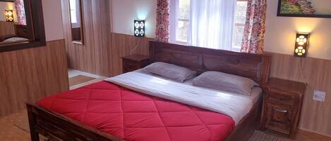 Quarto com cama de madeira, mesa de cabeceira, espelho e janela com cortinas.