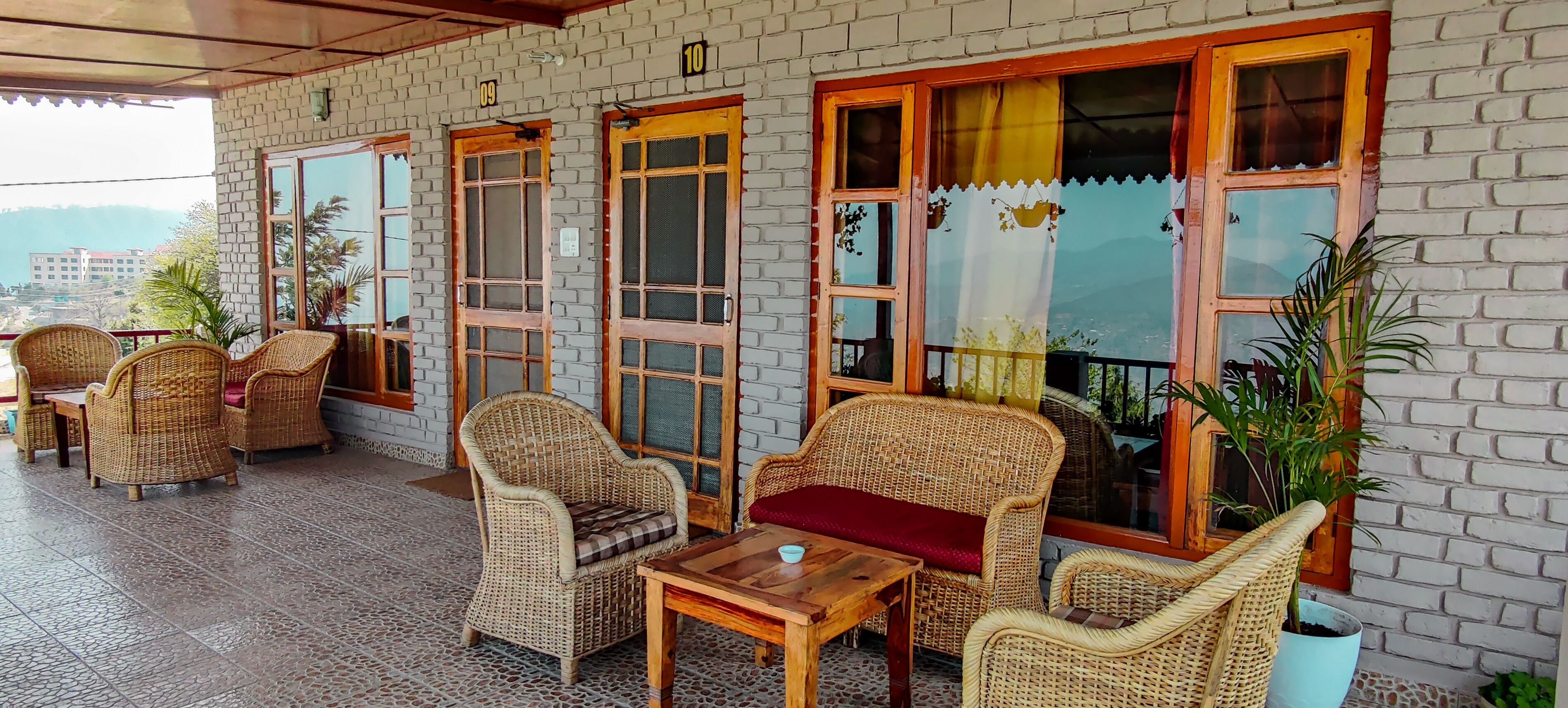 A covered patio area with wicker furniture and large windows.