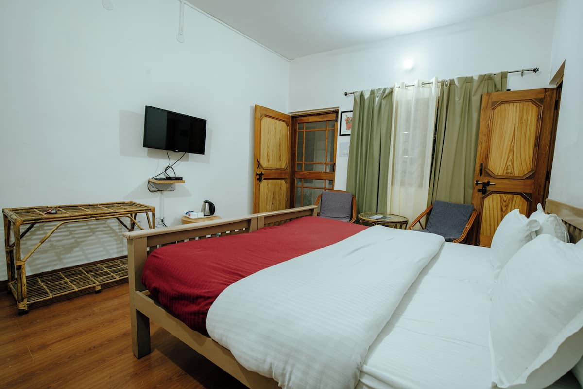 Hotellihuone, jossa on sänky, televisio, pieni pöytä ja tuoli.