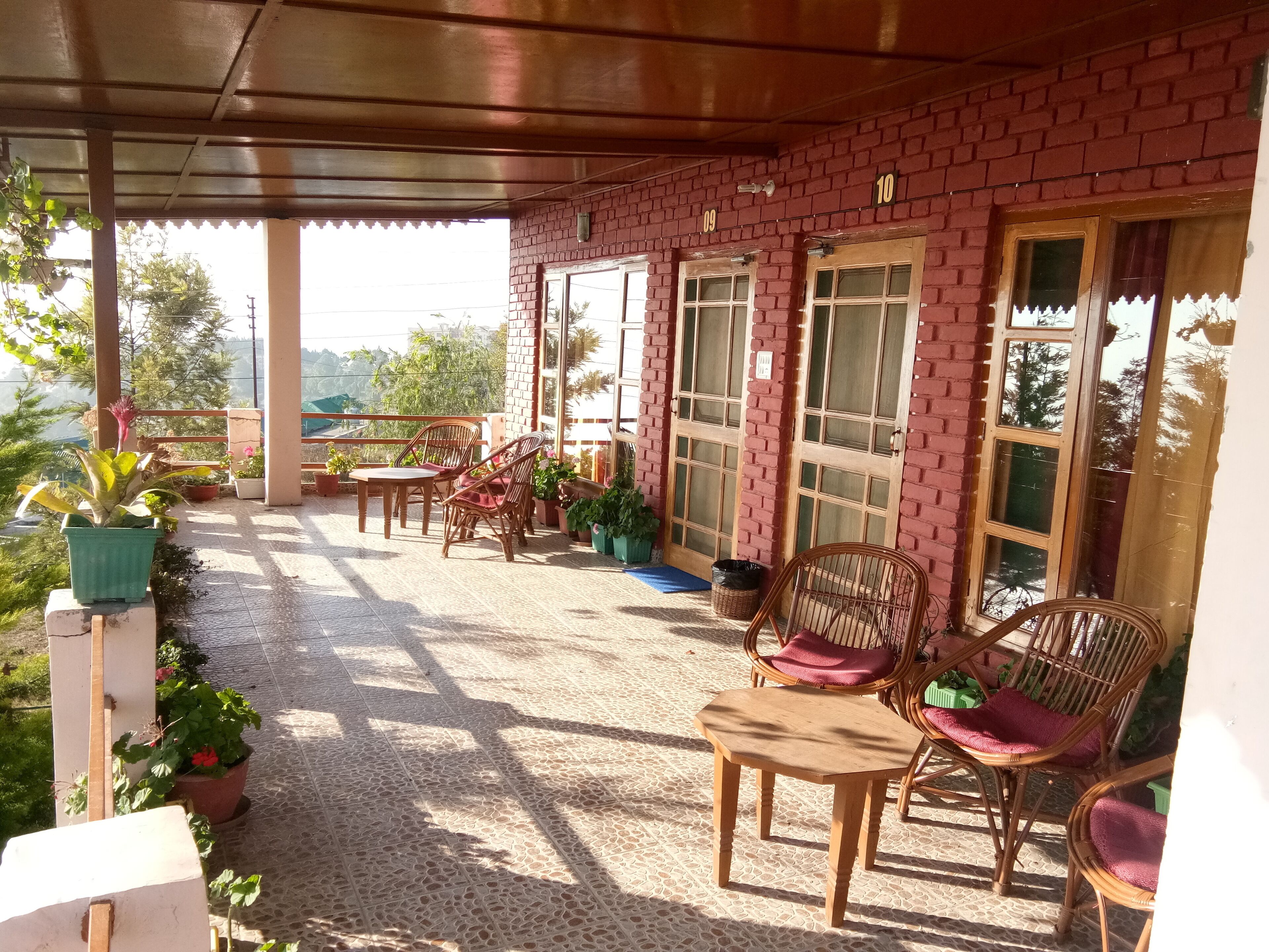 Un patio cubierto con paredes de ladrillo, mobiliario de madera y plantas en macetas.