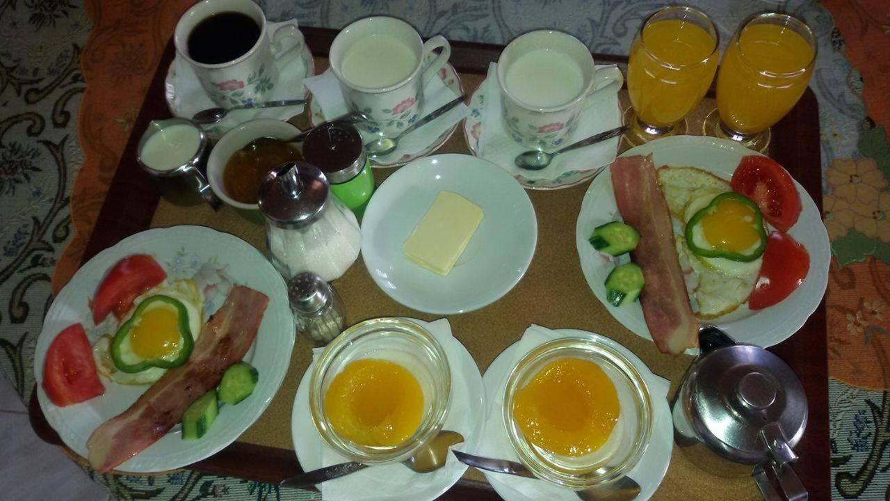 A breakfast tray with various items including eggs, bacon, toast, and beverages.