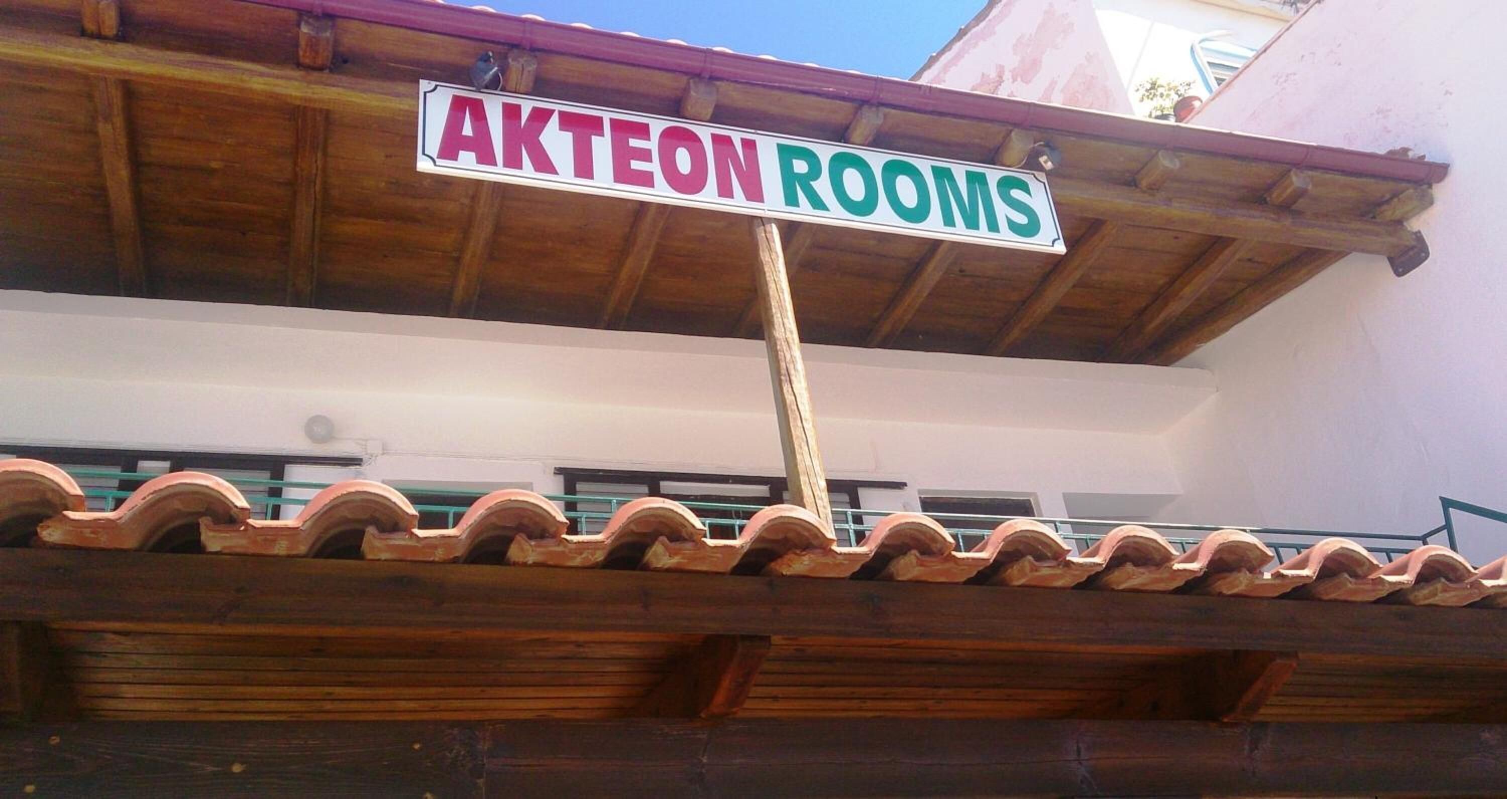 A sign for "AKTEON ROOMS" on a building's roof.