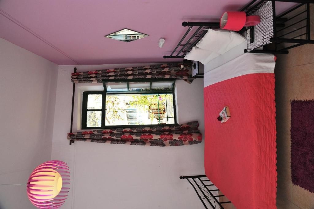 Une chambre avec un lit, une fenêtre donnant sur un beau paysage, un luminaire suspendu et une bouche d’aération au plafond.
