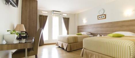 A hotel room with two beds, a desk, a chair, a lamp, a clock, and an air conditioning unit.