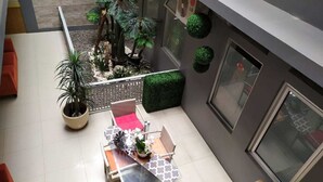 Un patio moderno al aire libre con una zona de estar, plantas en macetas y un pequeño jardín.