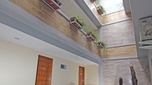 Un atrio de varios niveles con una mesa y sillas de cristal, sofás rojos y plantas en macetas.