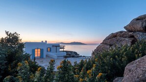 A coastal property with a white building, a view of the sea, and a rocky landscape. - Kanalia Villas (Mykonos)