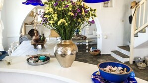 A dining area with a white table, a silver vase with flowers, and a blue bowl with mushrooms. - Kanalia Villas (Mykonos)