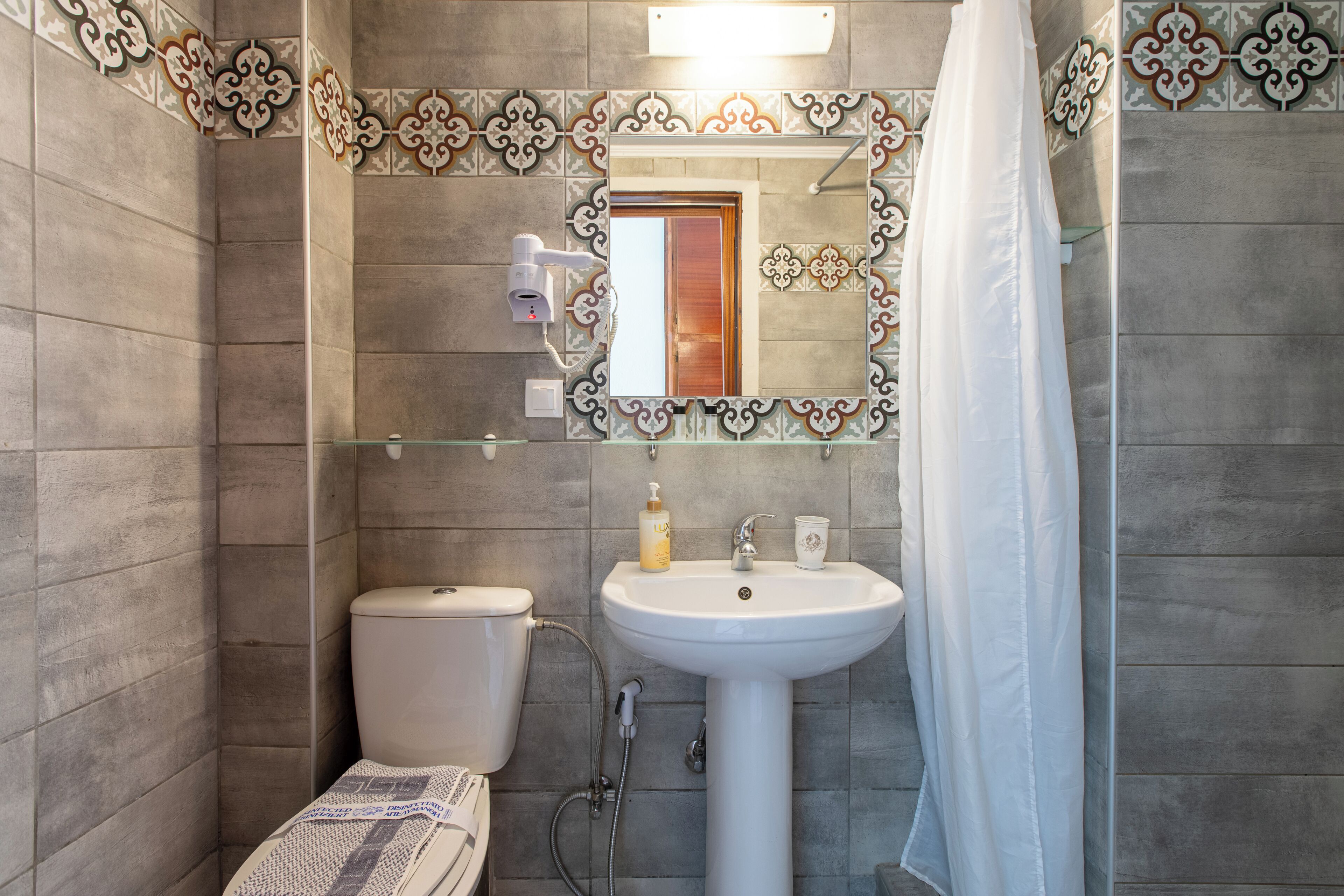 A bathroom with a toilet, sink, and mirror.