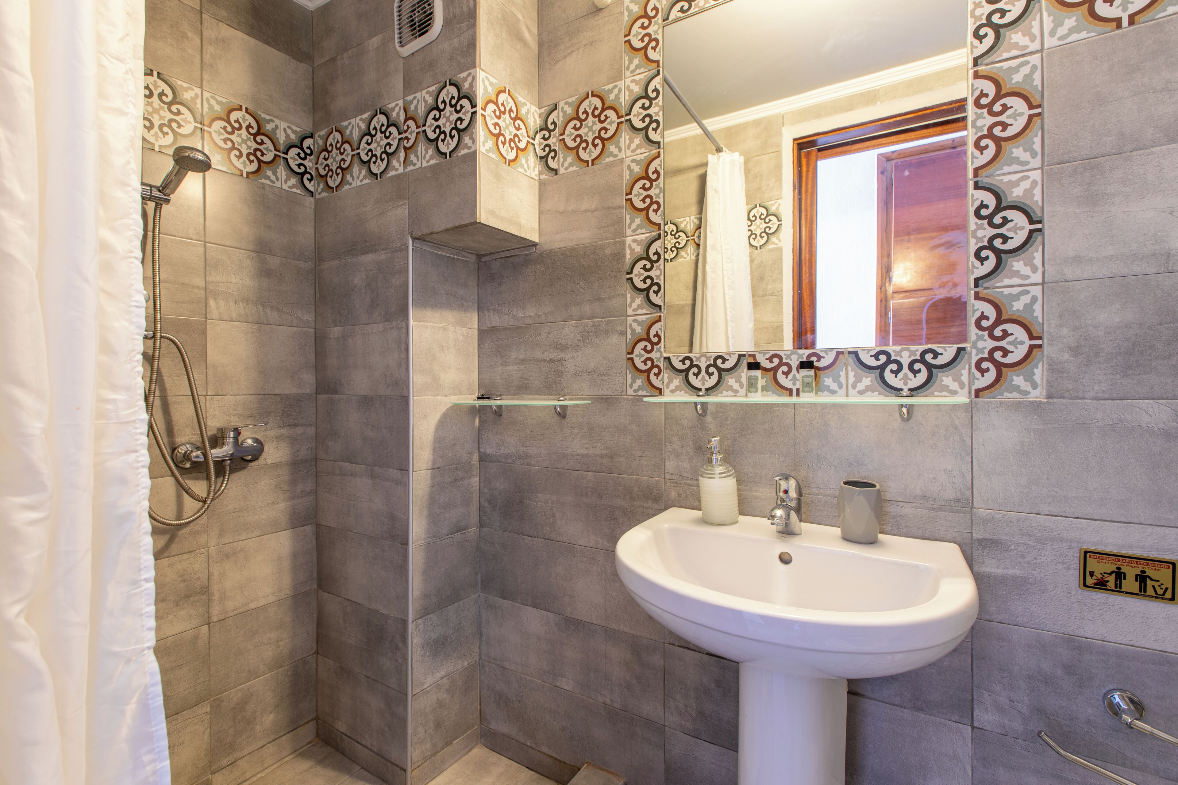 A bathroom with a shower, a sink, and a mirror.