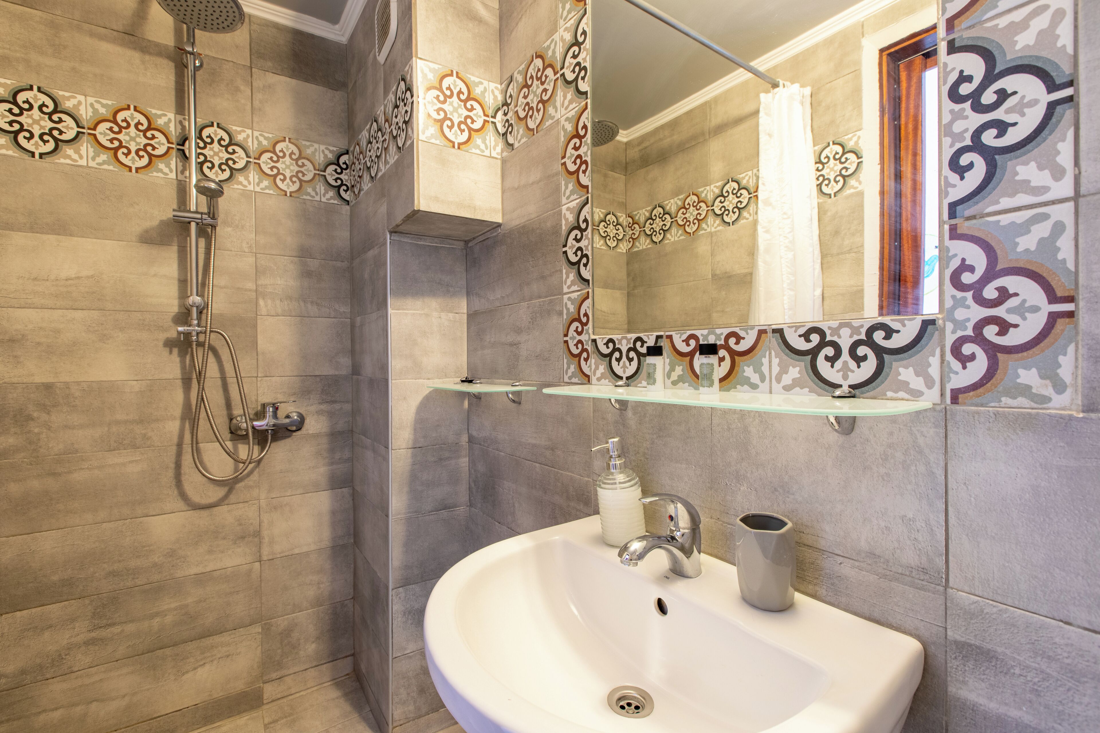 A bathroom with a shower, sink, and decorative tiles.