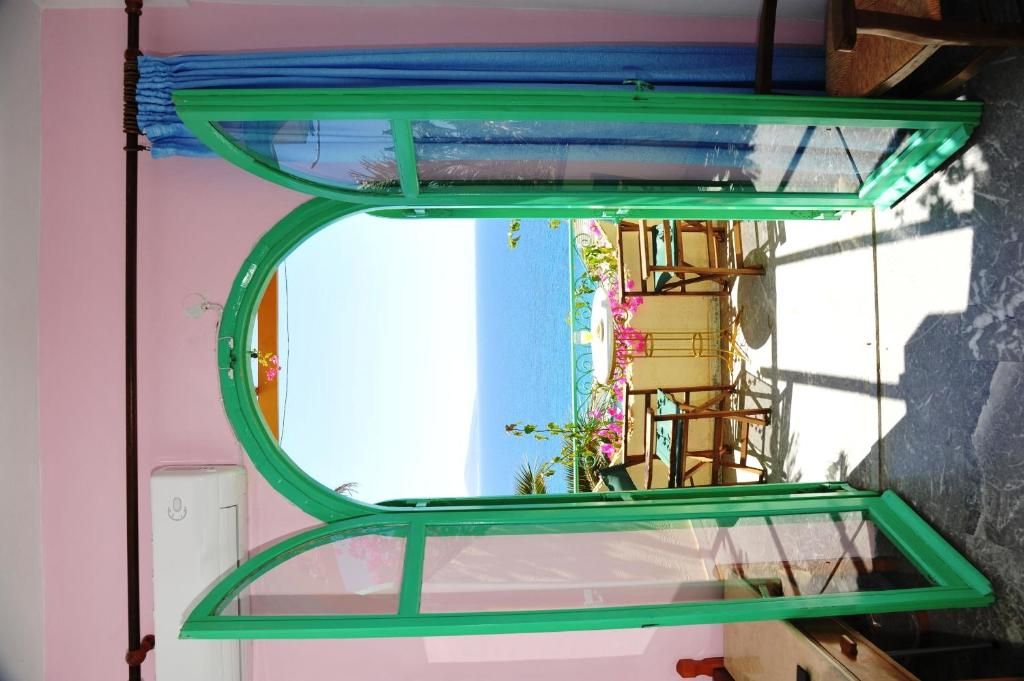 Una habitación con un ventanal grande que da a la playa, una cama y una silla.