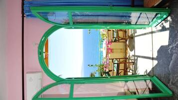 Una habitación con un ventanal grande que da a la playa, una cama y una silla.