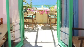 A balcony with a view of the sea, a table with chairs, and a window with curtains. - Erofili Rooms (Agios Vasileios)