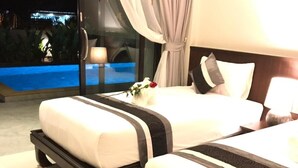 Habitación de hotel con dos camas, un ventanal con cortinas y vista a una piscina.
