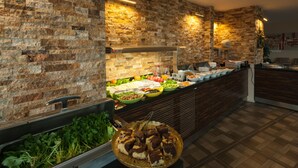 A buffet with a variety of food items and a brick wall backdrop. - Armin Hotel (Amasya)