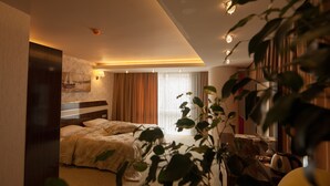 A hotel room with a bed, a desk, a chair, and a plant. - Armin Hotel (Amasya)