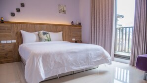 A neatly made bed with white linens, a wooden headboard, and a view of a balcony through a window with curtains. - Mysig (Luodong)