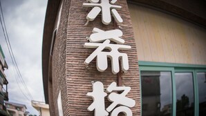 A building with a sign featuring large, white characters on a textured wall. - Mysig (Luodong)