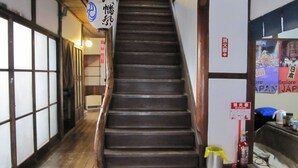 A wooden staircase in a traditional building with tatami mat flooring and shoji screens. - Taito Ryokan (Tokyo)