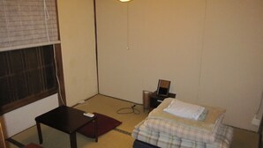A small, sparsely furnished room with a bed, a table, and a desk. - Taito Ryokan (Tokyo)