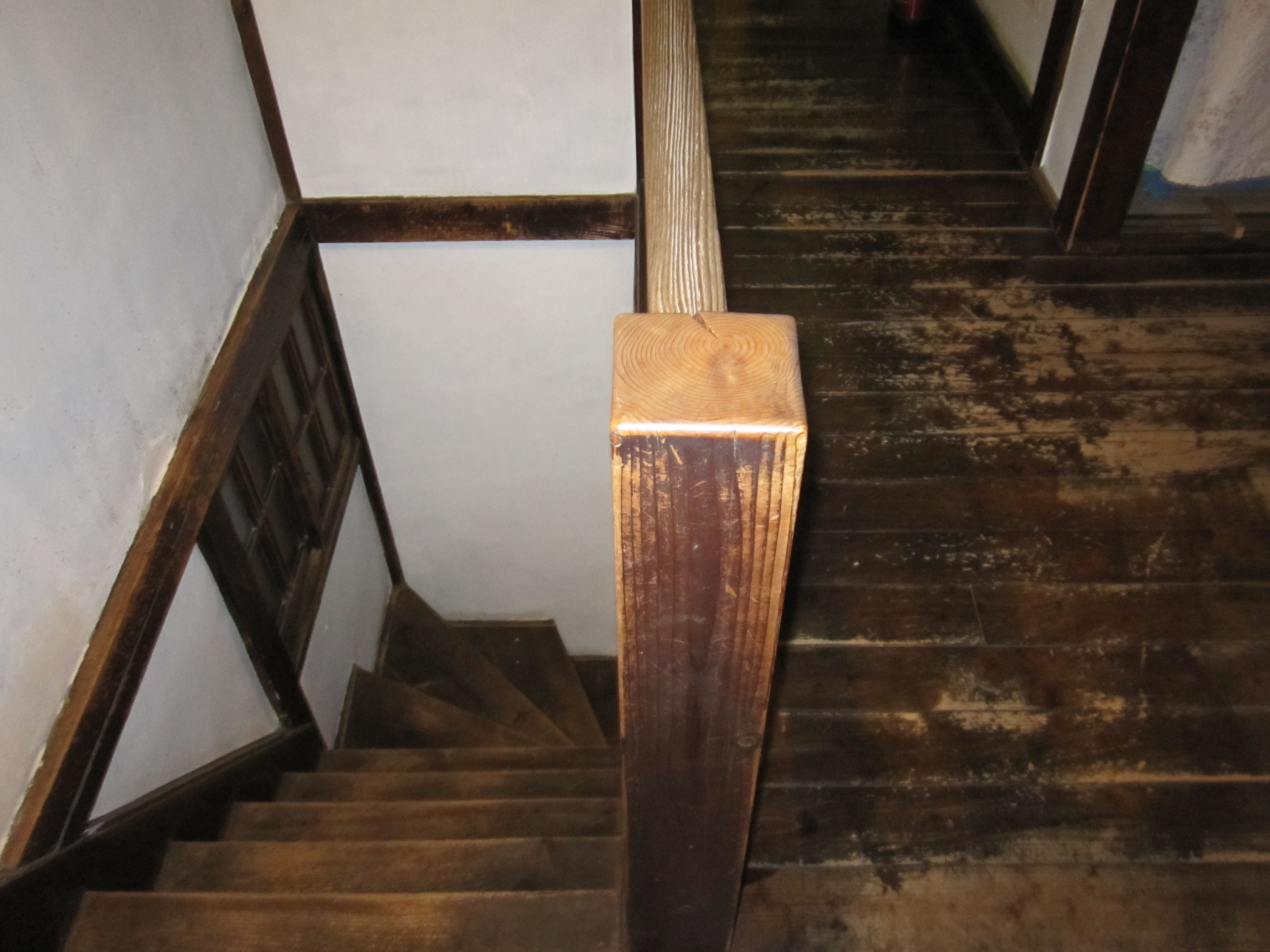 A wooden staircase with a handrail, wooden steps, and a dark wooden wall.