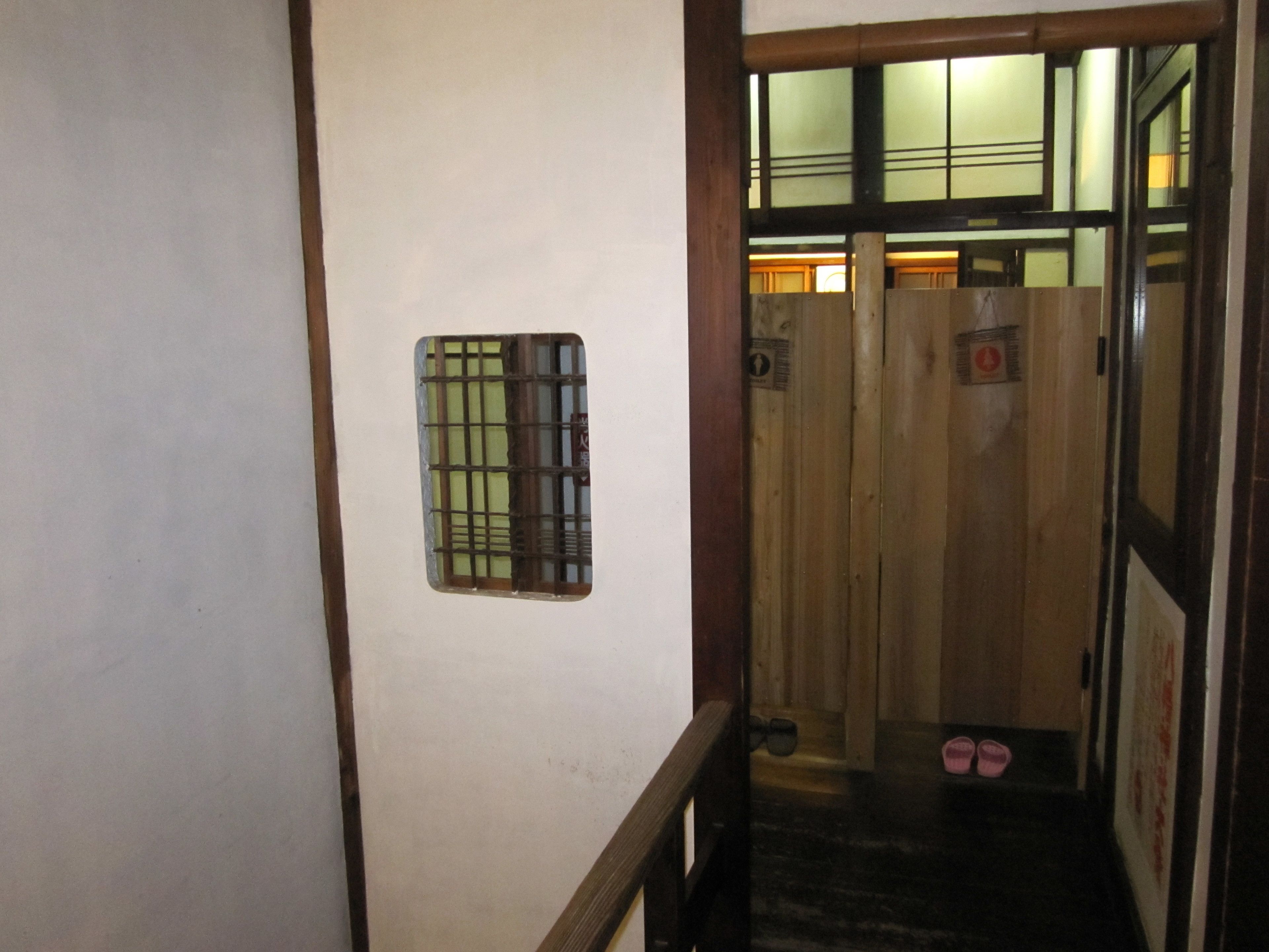 A narrow hallway with a wooden door and a small window with a grid pattern.