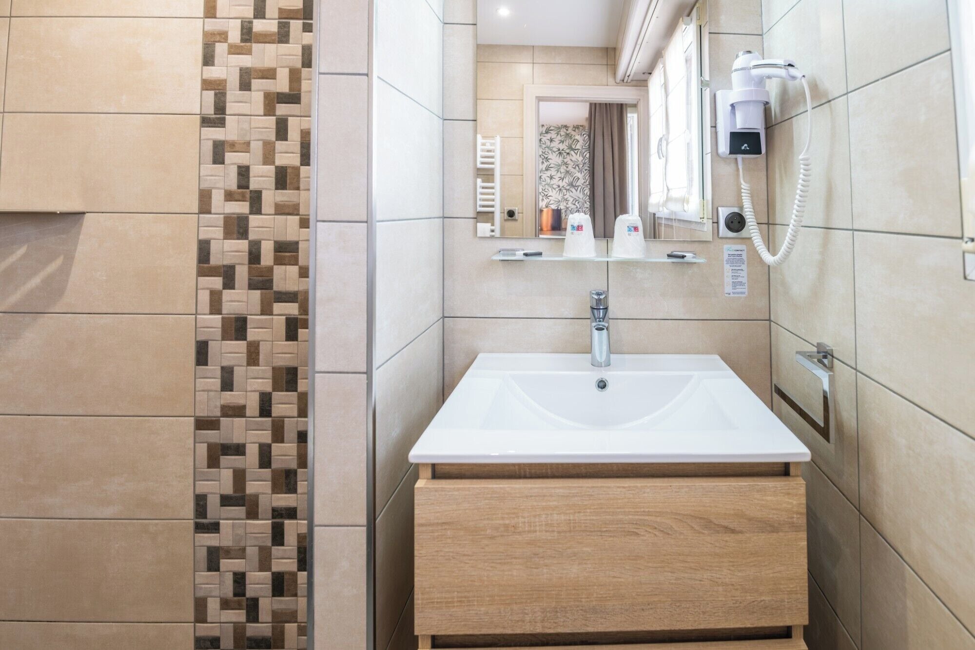 Une salle de bain moderne avec un lavabo blanc, un meuble-lavabo en bois et un porte-serviettes.