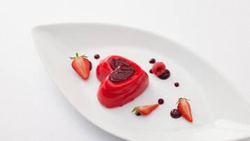 Un plato blanco con un postre rojo y fresas.