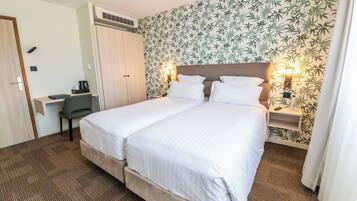 A double bed with a headboard, a desk with a chair, a wardrobe, and a wall with a bamboo leaf pattern.