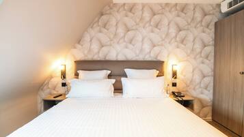 Une chambre d’hôtel avec un grand lit, deux tables de chevet avec des lampes, une armoire en bois et un mur à texture.