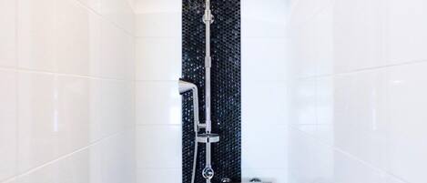 Eine Dusche mit schwarzer Wand mit Struktur und chromfarbenen Armaturen.