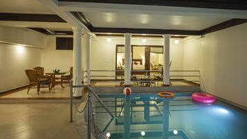 Una piscina con barandilla de vidrio, un flotador salvavidas y una silla junto a la piscina.