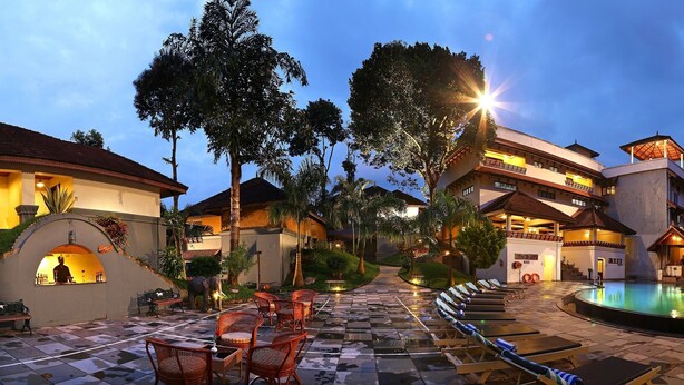 A resort with a pool, lounge chairs, and a bar area. - The Elephant Court (Peermade)