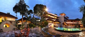 Un complejo turístico con piscina, sillas de descanso y zona de bar.