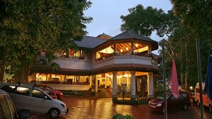 A two-story building with a covered entrance and a balcony. - The Elephant Court (Peermade)