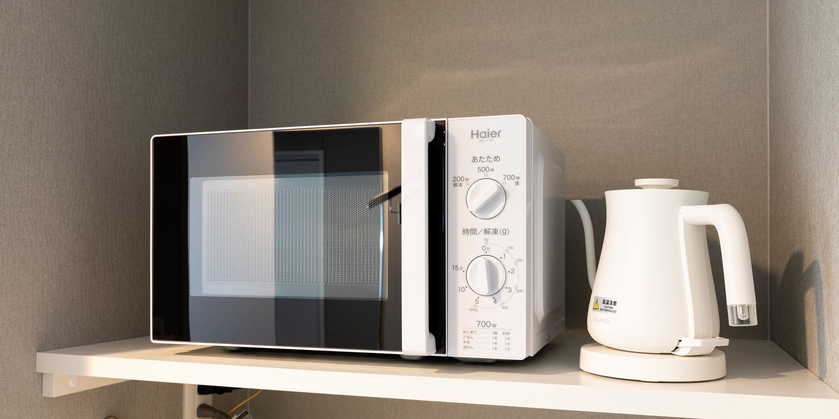 A microwave and a coffee maker on a white shelf.