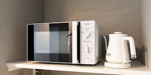 Un microondas y una cafetera sobre un estante blanco.