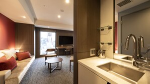 A modern hotel room with a sofa, a small table, a TV, and a kitchenette with a sink and mirror. - Tokyu Stay Sapporo (Sapporo)