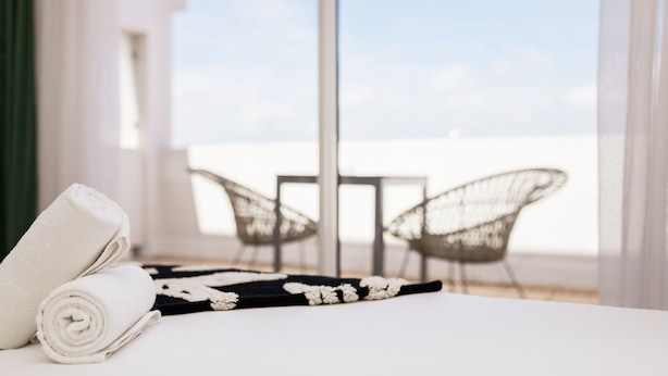 A hotel room with a bed, two wicker chairs, and a view of the sea. - Hôtel Les Sables - Urban Style - by Logis Hotels (Canet-en-Roussillon)